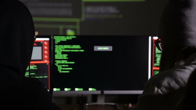 Team of hackers, hacking computers, working in dark room. HD