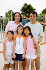 Family standing at playground, smiling at camera