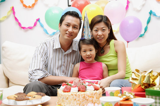 Family with one child sitting with birthday cake, portrait