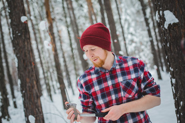 bearded man with an hatchet in the winter forest