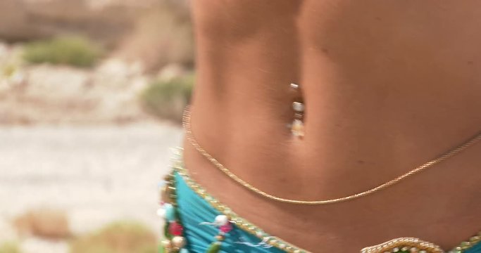 Belly dancer. Beautiful belly dancer dancing ethnic dances in a desert. In sexy green blue dress dancing . Bust , belly piercings. close up. 2 . 4K
