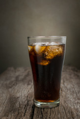 glass of cola with ice cubes on wood table , soft drink.