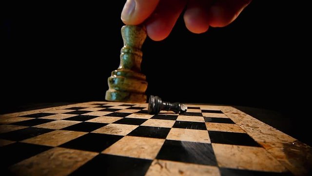A white chess piece king overthrows the black king on a chess board...