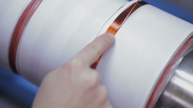 Worker operates with electric cooper wires, winding of the transformer. HD.