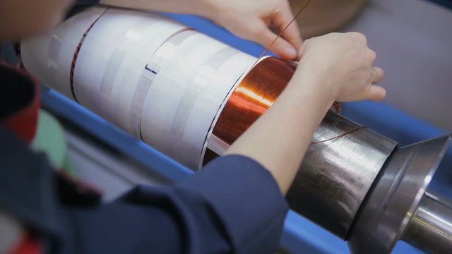 Worker operates with electric cooper wires, winding of the transformer. HD.