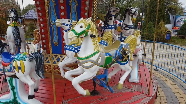 Old fashioned carousel horses in autumn park. Steadicam shot.