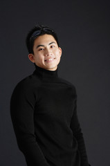 Young man dressed in black, standing against black background