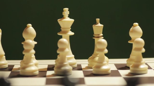 Panning shot of a chess board, with white pieces in focus.
