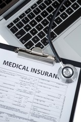 Clipboard with medical insurance paper, stethoscope and laptop