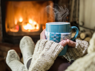 Warming and relaxing near fireplace with a cup of hot drink.