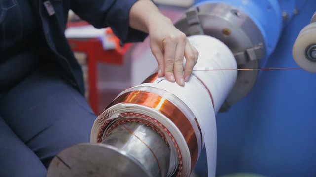 Transformer, engine production. Worker winding cooper wires on a high voltage transformer. Slider shoot. HD.
