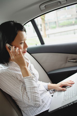 Businesswoman in car on the phone and using laptop