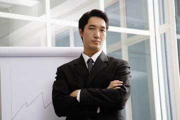 Fototapeta premium Businessman standing next to flipchart, looking at camera