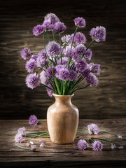 Bouquet of onion (chives) flowers in the vase on the wooden tabl
