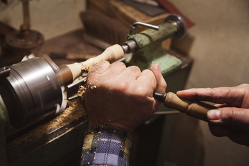 Man makes wood detail on lathe