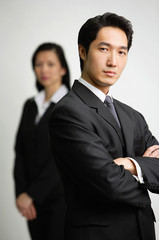Businessman with arms crossed, woman in the  background