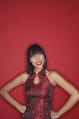 Woman dressed in cheongsam, hands on hips, smiling