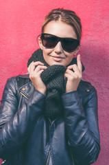 Portrait of young caucasian woman with sunglasses looking at camera and standing against of purple ...