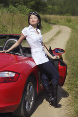 Woman leaning on red sports car, portrait