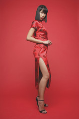 Woman wearing cheongsam and high heels, looking at camera