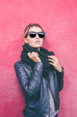 Portrait of young caucasian woman with sunglasses looking at camera and standing against of purple  background