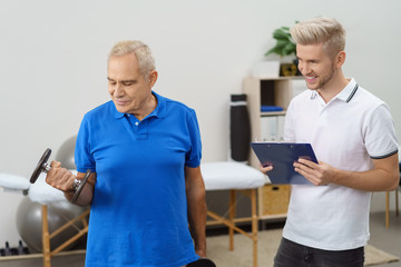 senior trainiert mit hanteln mit einem physiotherapeut