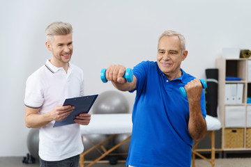 senior trainiert mit kleinen hanteln in der physiotherapie