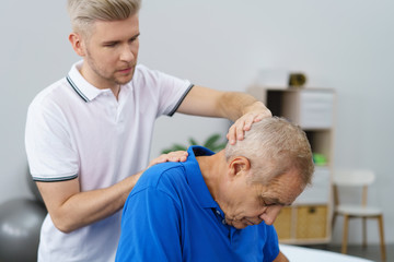 senior mit nackenschmerzen in der behandlung beim physiotherapeuten