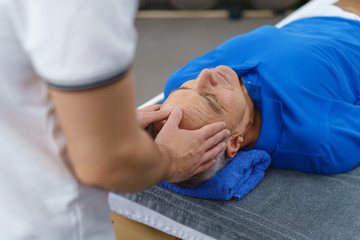 osteopath behandelt einen älteren patienten in seiner praxis