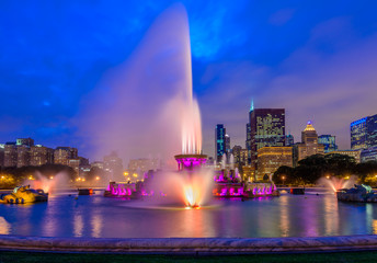 Chicago skyline panorama with skyscrapers and Buckingham fountain in Grant Park at night lit by colorful lights.