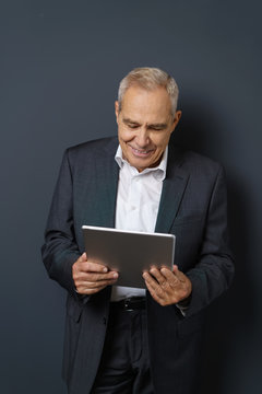 älterer unternehmer schaut auf sein tablet