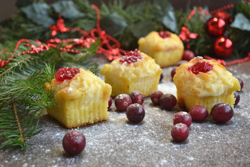Christmas baking. Mini cupcakes with sweet cream cheese filling decorated cranberry jam and fresh cranberries on powdered sugar background. Festive curd dessert. Soft focus.