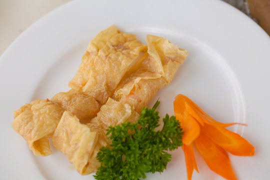 Yellow crispy deep fried bean curd stuffed with pork and shrimp in decorated dish