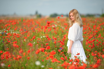 Fototapeta na wymiar girl in white dress in the poppy field