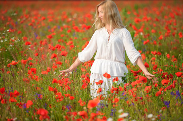 Naklejka na ściany i meble portrait of a beautiful woman in a field with flowers