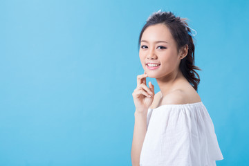 Asian cute young girl holding cosmetic product in white shirt showing her skin in light blue background