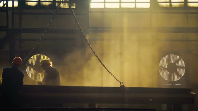 workers at the plant or factory processed metal. Purify by rust, sanded and polished by hand. Flying dust. Large shop windows, the sun's rays. It looks like an old factory of the Great Depression