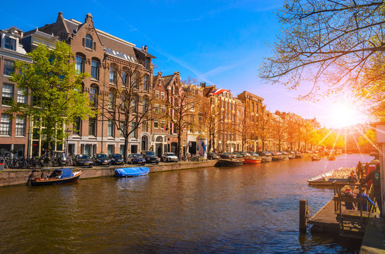 Traditional old buildings and and boats at the sunset in Amsterdam, Netherlands