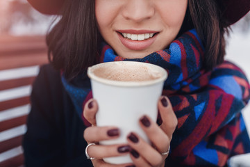 Woman drinking hot takeaway cup of coffee on winter street