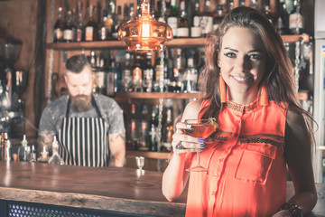 Beautiful girl is drinking a cocktail with ice vapor in the bar