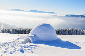 Big round igloo stands on mountains covered with snow.