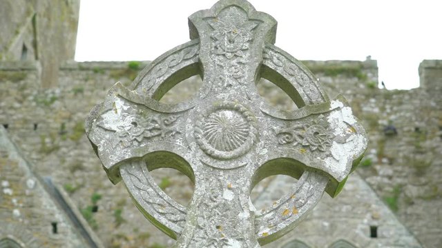 A celtic on the high cross in Ireland a tomsbstone outside an old ruined building