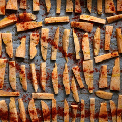 Sweet potato slices organized in a baking pan, before baking. With origano and sweet pepper powder on top. Top view.
