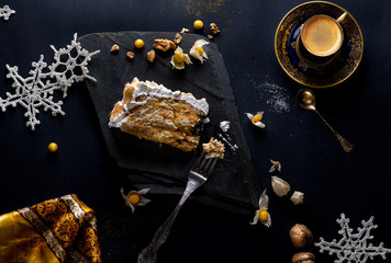 piece of cake and a cup of coffee on a black background decorated with New Year