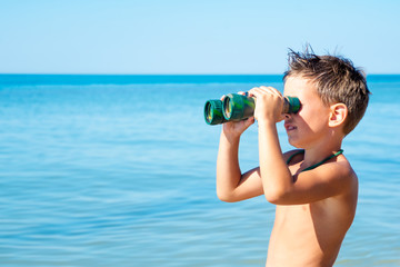boy looks through binoculars and sees sea