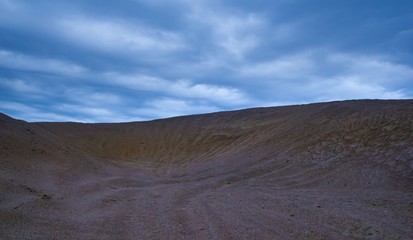 Fototapeta na wymiar Sand dunes under cloudy sky at evening