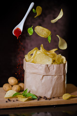 Potato chips flying over a bowl.