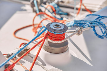 Tangled ropes on the winch on a yacht on background port and blue water