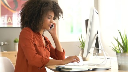 Cheerful businesswoman talking on phone in office - Powered by Adobe