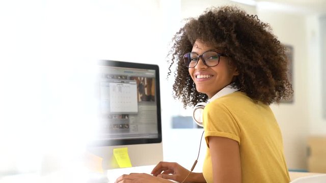 Cheerful mixed-race girl designing in office on computer